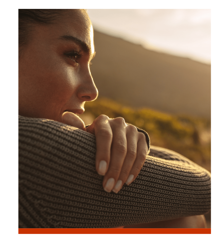Close-up of a woman reflecting outdoors in warm sunlight.
