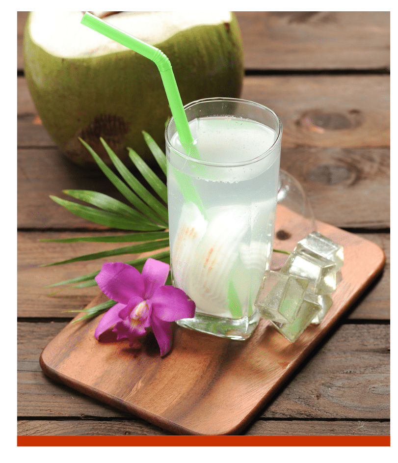 Refreshing coconut drink with a straw on a wooden tray.