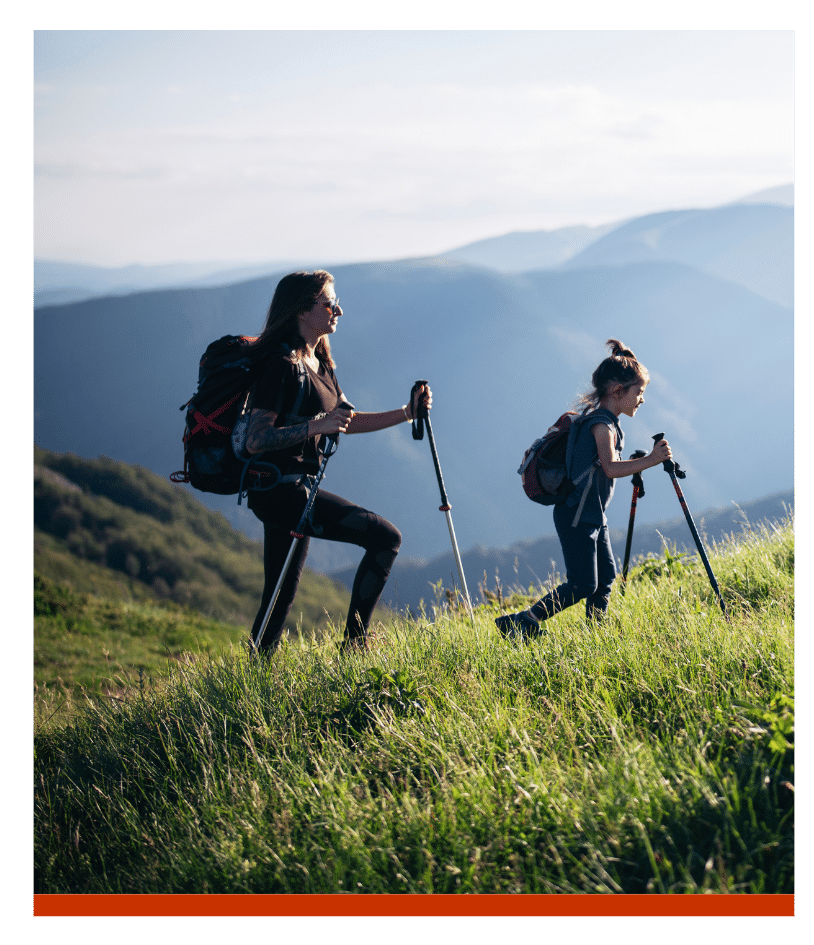 Mother and daughter hiking in the mountains with trekking poles.
