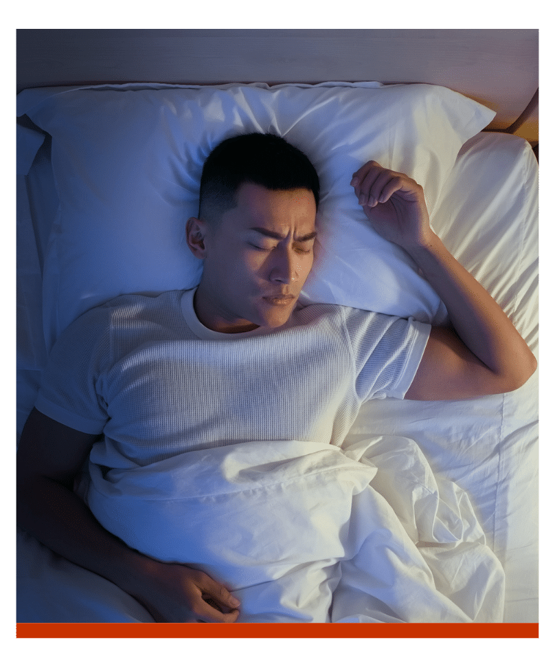 Man sleeping peacefully in a dimly lit bedroom.