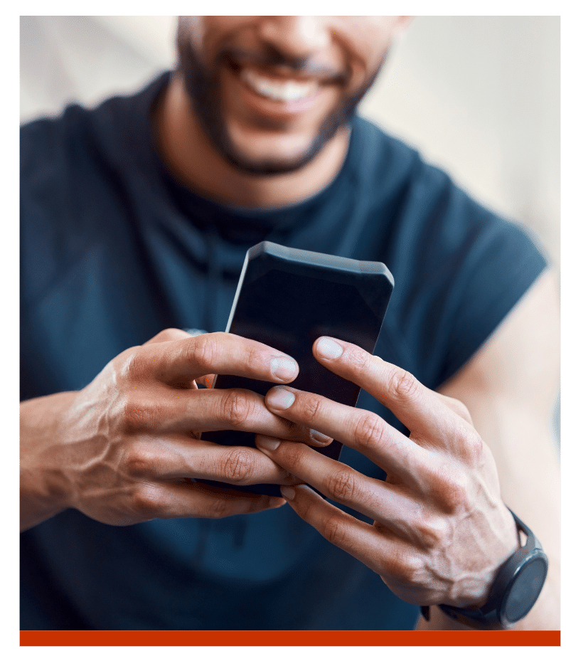 Close-up of a man smiling while using his smartphone.