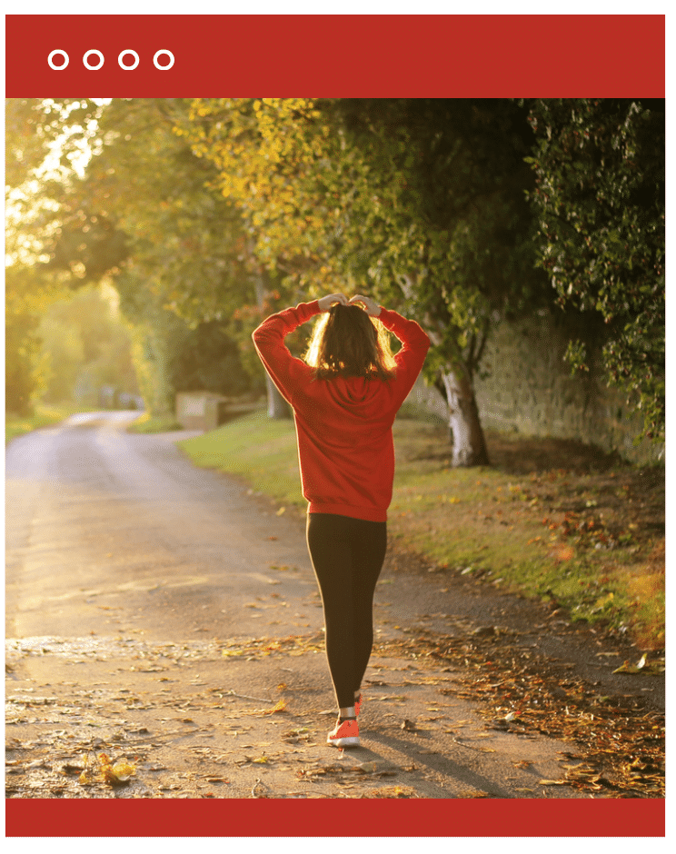 Person walking down a tree-lined path in morning light, symbolizing calm and daily movement.