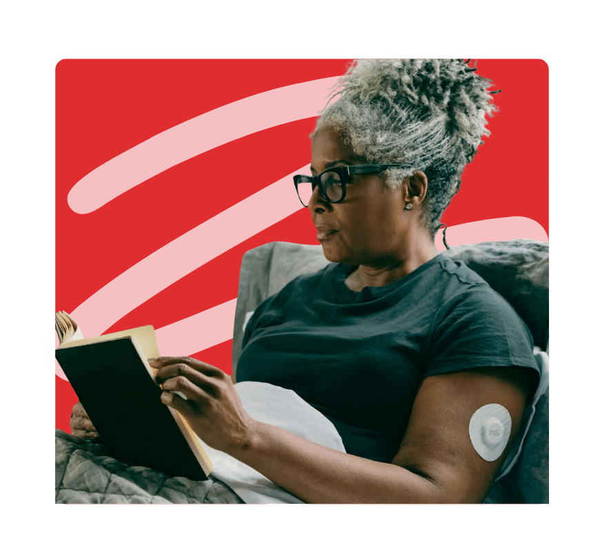 Woman with CGM sensor on arm reading a book during Diabetes Awareness Month